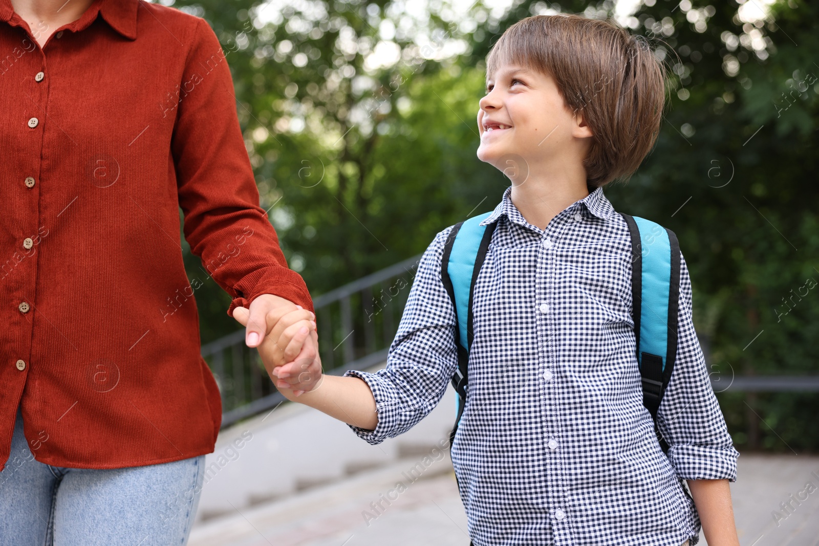 Photo of Mother taking her son to school outdoors, closeup