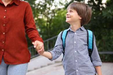 Photo of Mother taking her son to school outdoors, closeup