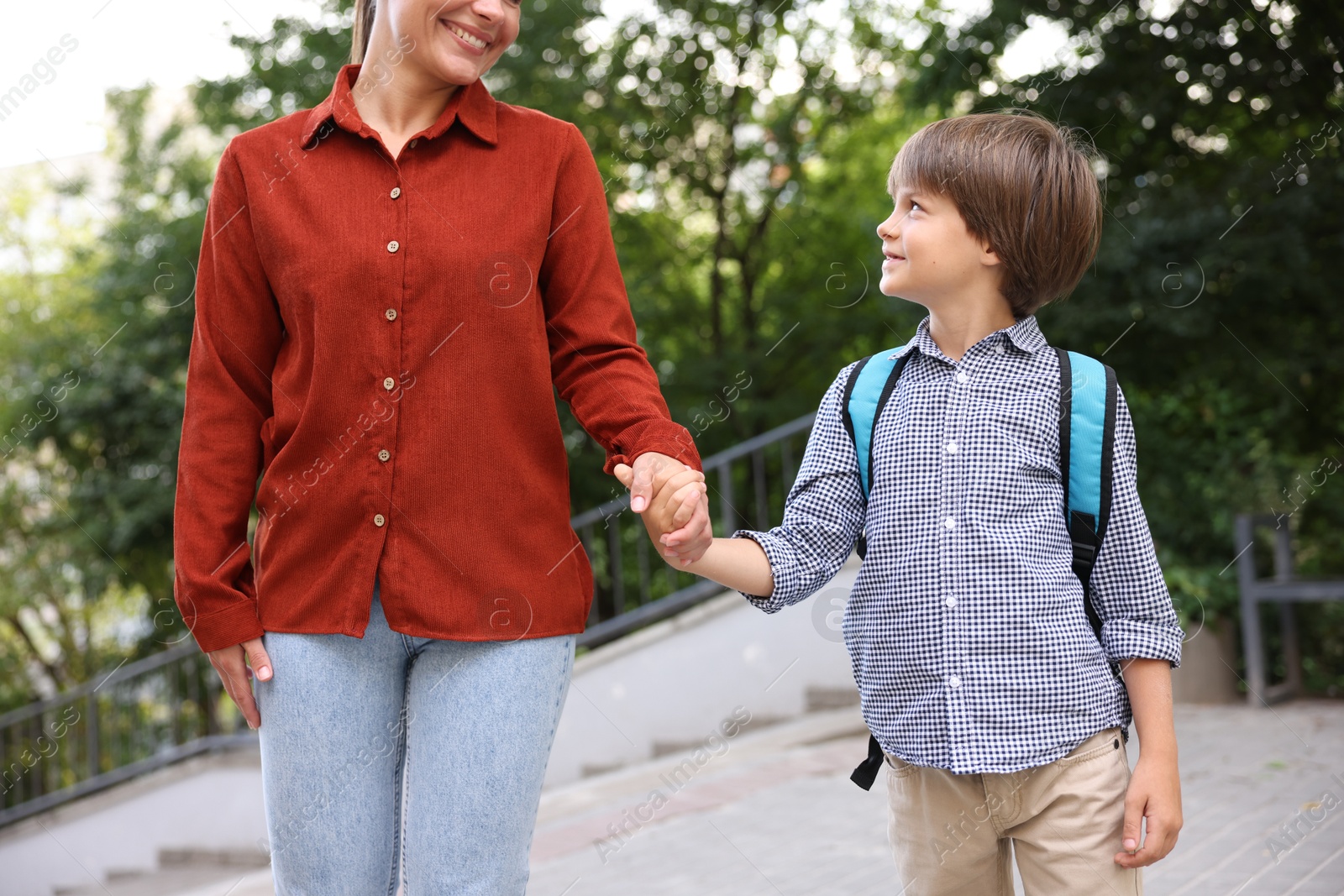 Photo of Mother taking her son to school outdoors, closeup