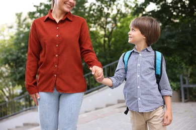 Photo of Mother taking her son to school outdoors, closeup