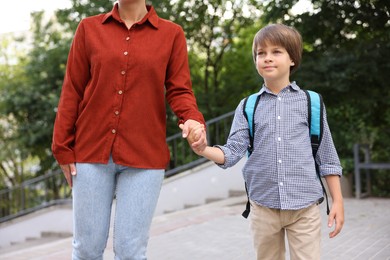 Photo of Mother taking her son to school outdoors, closeup