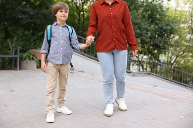 Photo of Mother taking her son to school outdoors, closeup