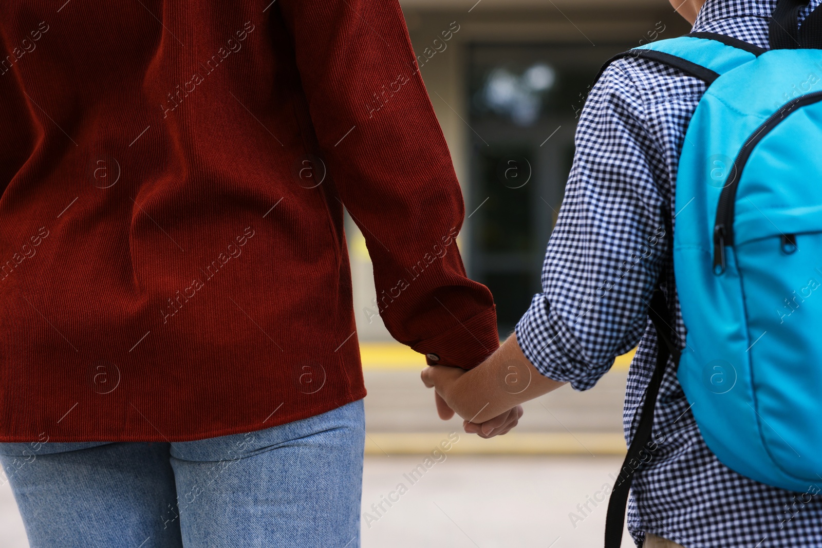 Mother holding hands with her son and taking him to school outdoors, closeup Photo of Mother holding hands with her son and taking him to school outdoors, closeup