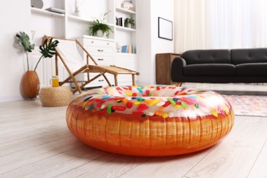 Photo of Bright inflatable donut shaped ring on wooden floor indoors. Dreaming about vacation at sea