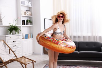 Photo of Happy woman in sunglasses and straw hat with inflatable ring having fun at home. Dreaming about vacation at sea