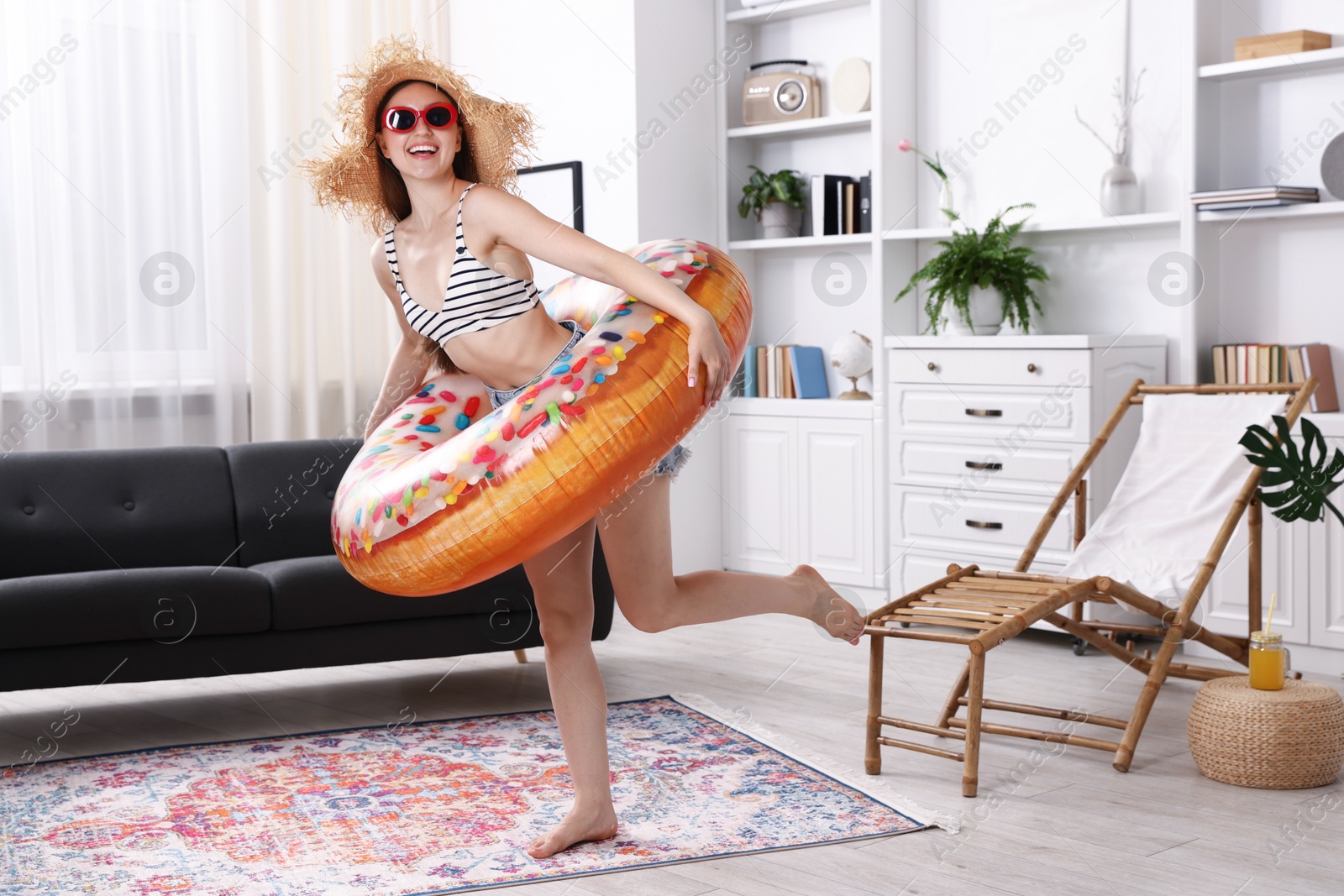 Happy woman in sunglasses and straw hat with inflatable ring having fun at home. Dreaming about vacation at sea Photo of Happy woman in sunglasses and straw hat with inflatable ring having fun at home. Dreaming about vacation at sea
