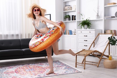 Photo of Happy woman in sunglasses and straw hat with inflatable ring having fun at home. Dreaming about vacation at sea