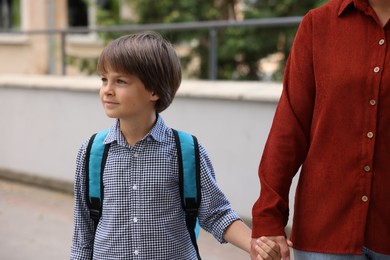 Photo of Mother taking her son to school outdoors, closeup