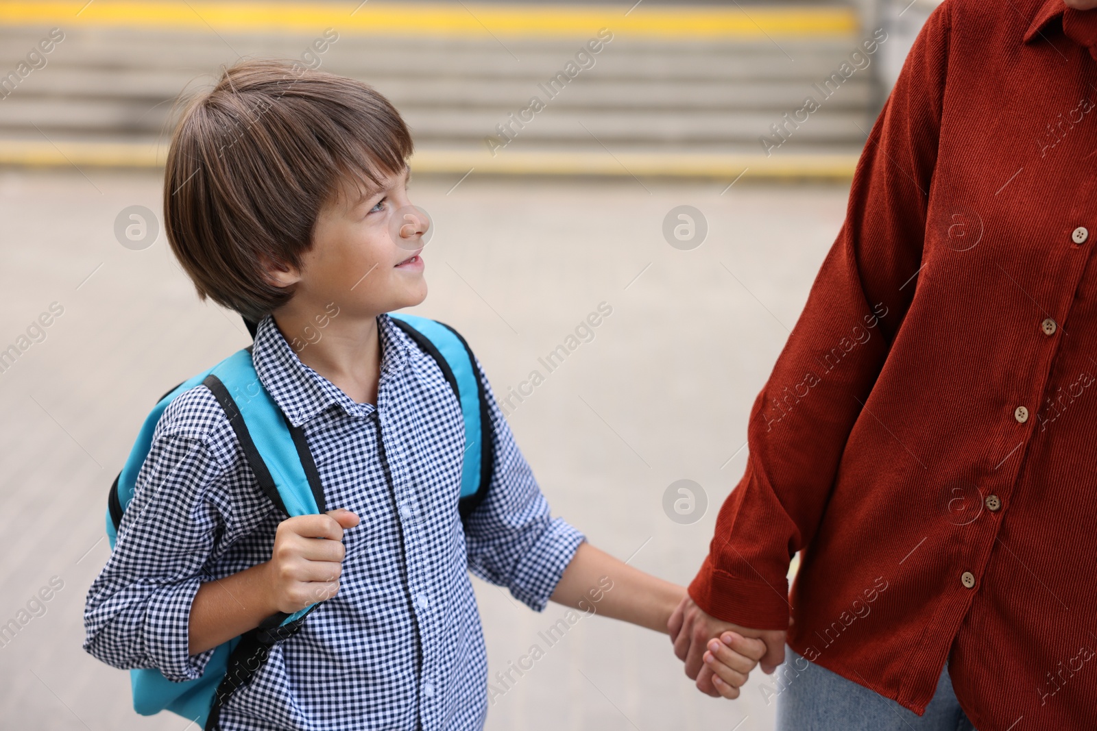 Photo of Mother taking her son to school outdoors, closeup
