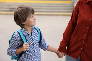 Photo of Mother taking her son to school outdoors, closeup