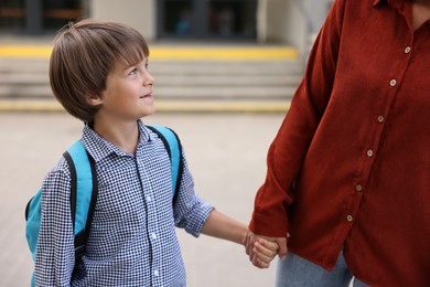 Photo of Mother taking her son to school outdoors, closeup
