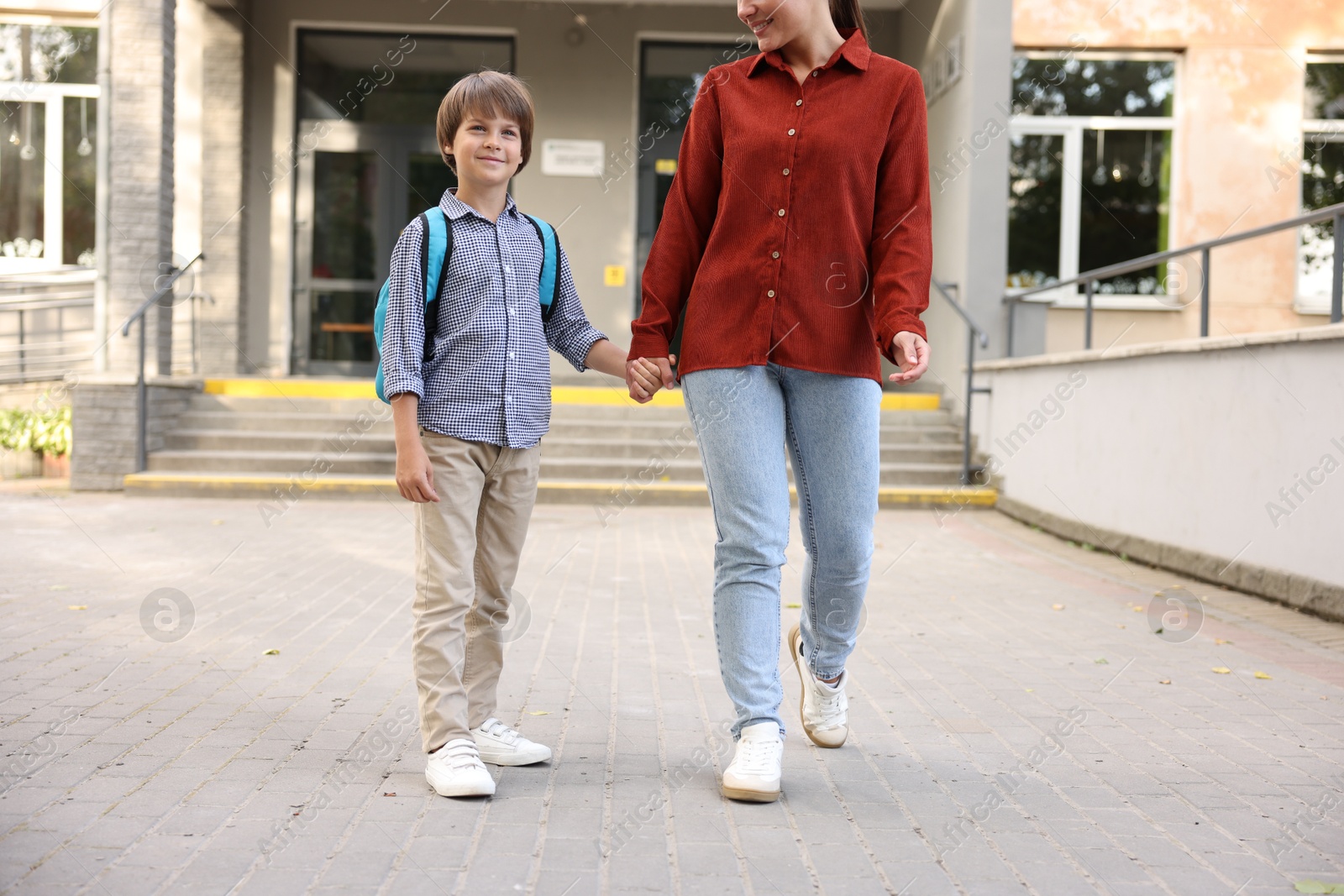 Photo of Mother taking her son to school outdoors, closeup