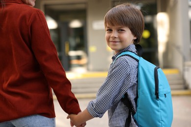Photo of Mother taking her son to school outdoors, closeup