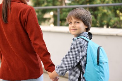 Photo of Mother taking her son to school outdoors, closeup
