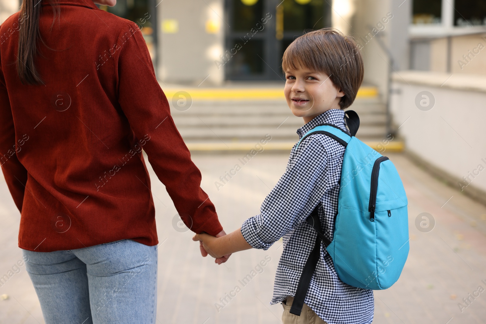 Photo of Mother taking her son to school outdoors, closeup