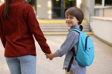 Photo of Mother taking her son to school outdoors, closeup