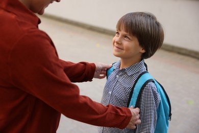 Photo of Mother taking her son to school outdoors, closeup