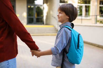 Photo of Mother taking her son to school outdoors, closeup