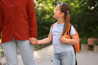 Photo of Mother taking her daughter to school outdoors, closeup