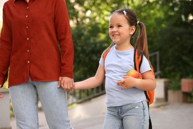 Photo of Mother taking her daughter to school outdoors, closeup