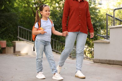 Photo of Mother taking her daughter to school outdoors, closeup