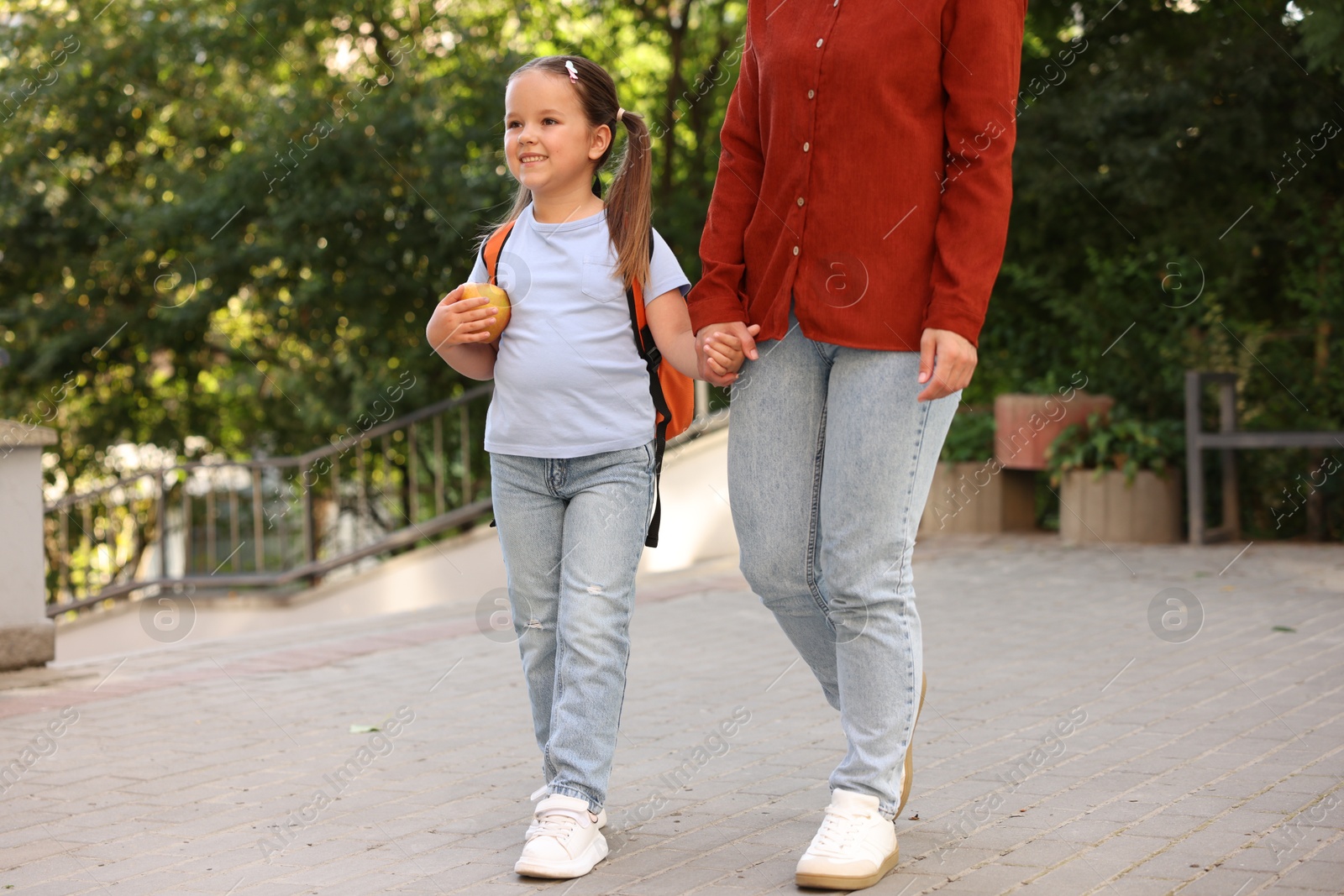 Mother taking her daughter to school outdoors, closeup Photo of Mother taking her daughter to school outdoors, closeup