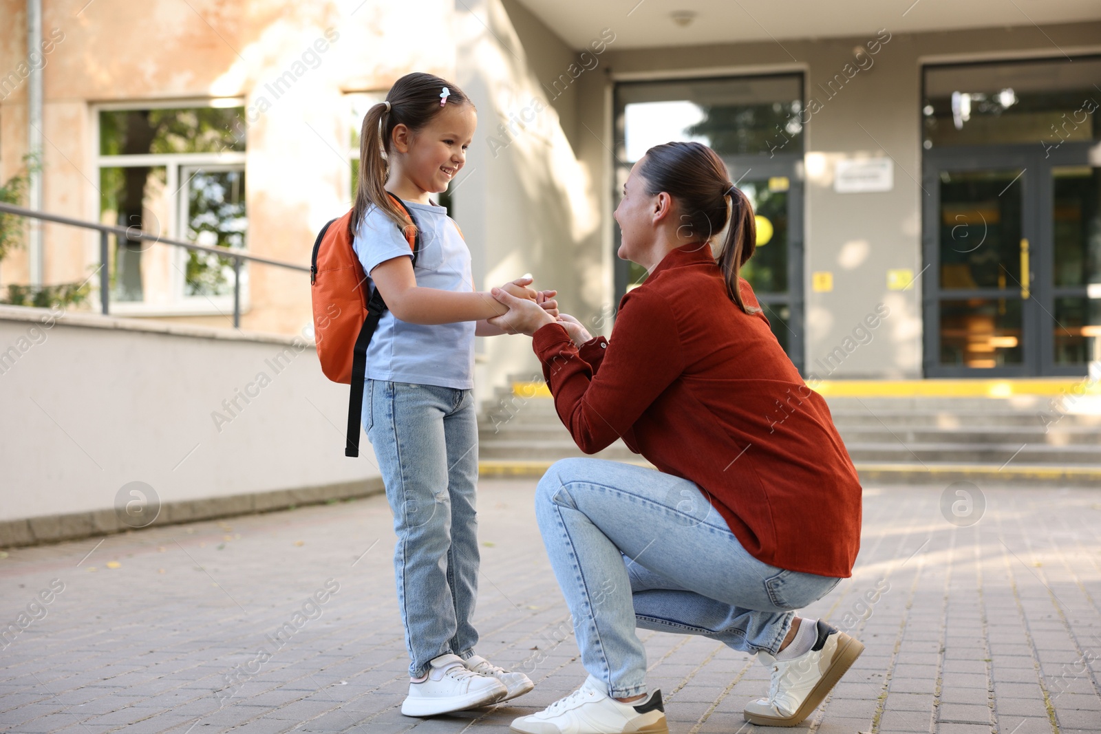 Mother taking her daughter to school outdoors Photo of Mother taking her daughter to school outdoors