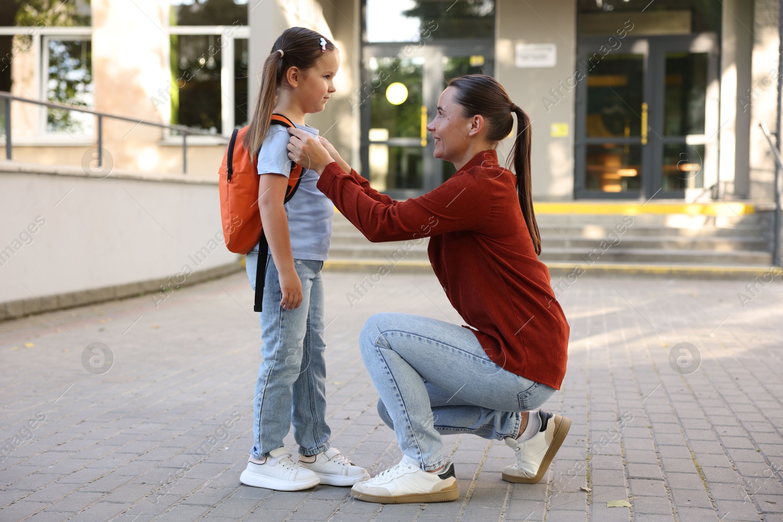 Mother taking her daughter to school outdoors Photo of Mother taking her daughter to school outdoors