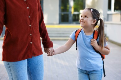 Photo of Mother taking her daughter to school outdoors, closeup
