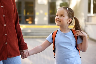 Photo of Mother taking her daughter to school outdoors, closeup