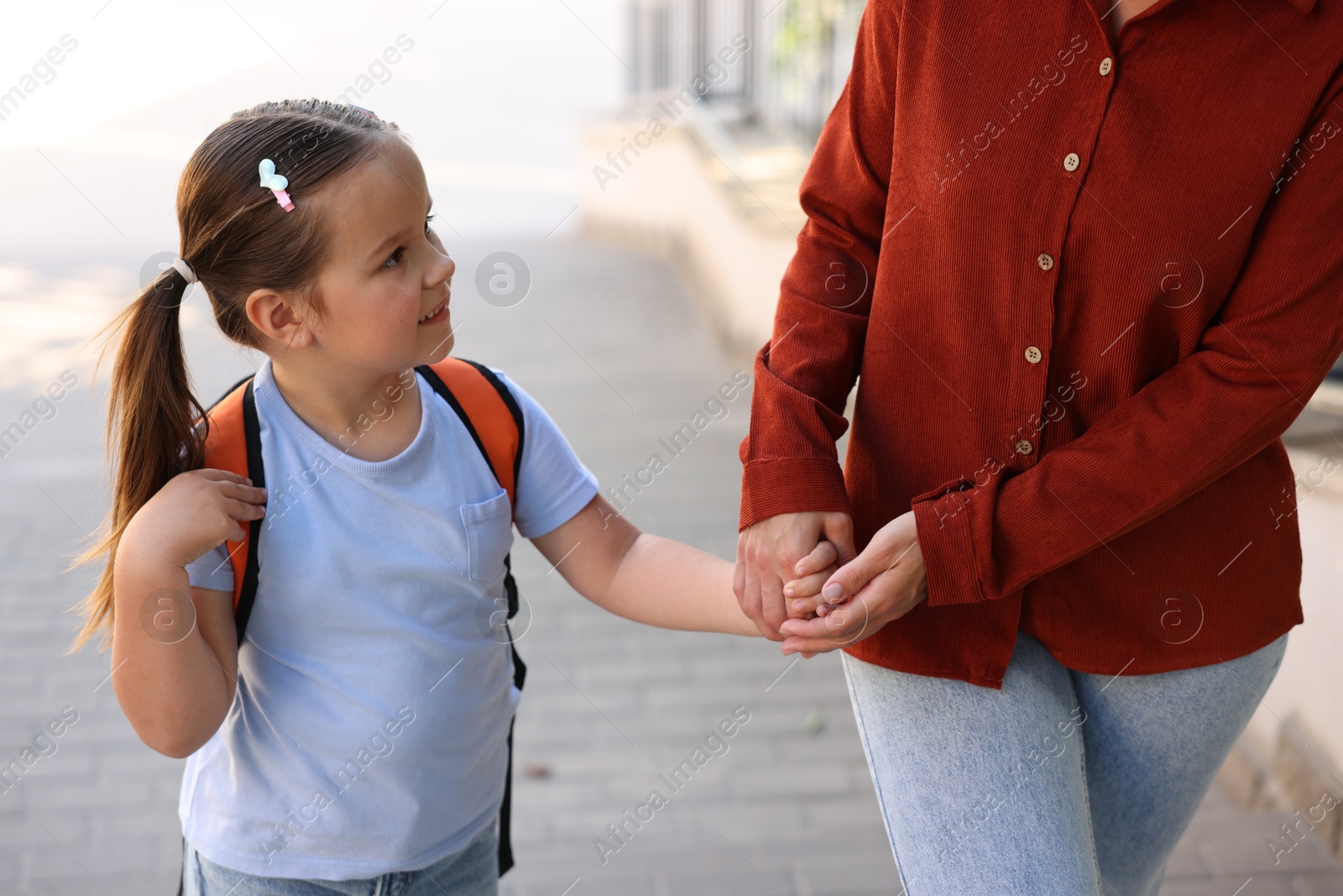 Mother taking her daughter to school outdoors, closeup Photo of Mother taking her daughter to school outdoors, closeup