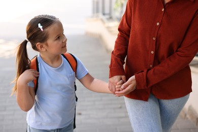 Photo of Mother taking her daughter to school outdoors, closeup