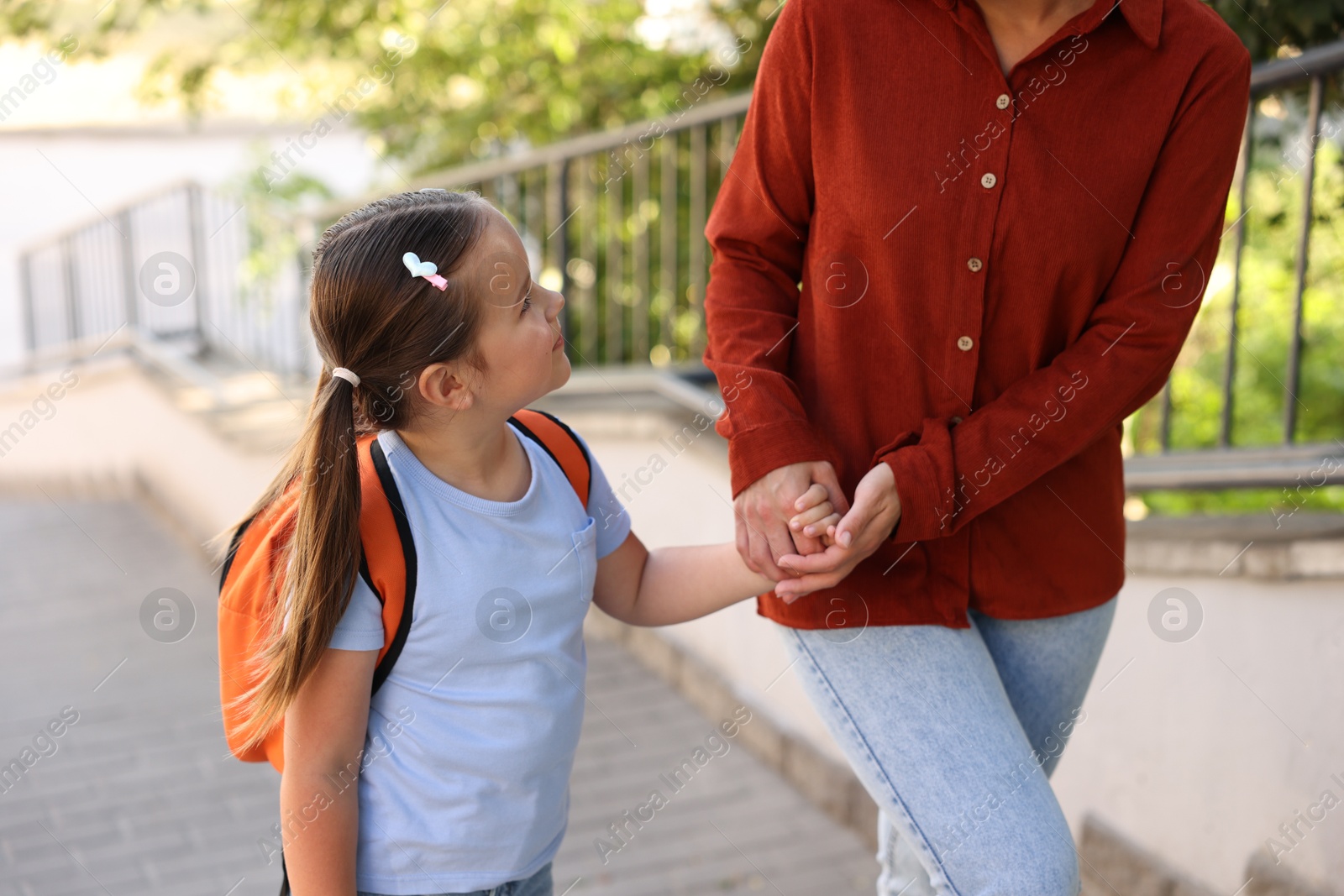 Mother taking her daughter to school outdoors, closeup Photo of Mother taking her daughter to school outdoors, closeup