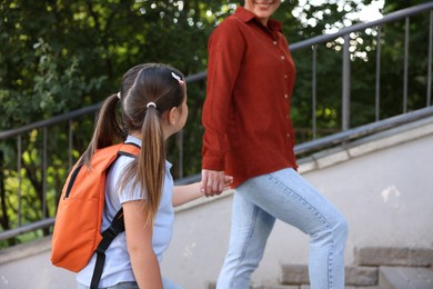 Photo of Mother taking her daughter to school outdoors, closeup