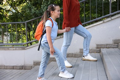 Photo of Mother taking her daughter to school outdoors, closeup