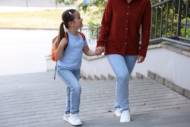 Photo of Mother taking her daughter to school outdoors, closeup
