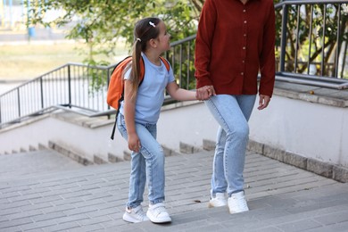 Photo of Mother taking her daughter to school outdoors, closeup