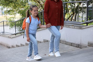 Photo of Mother taking her daughter to school outdoors, closeup