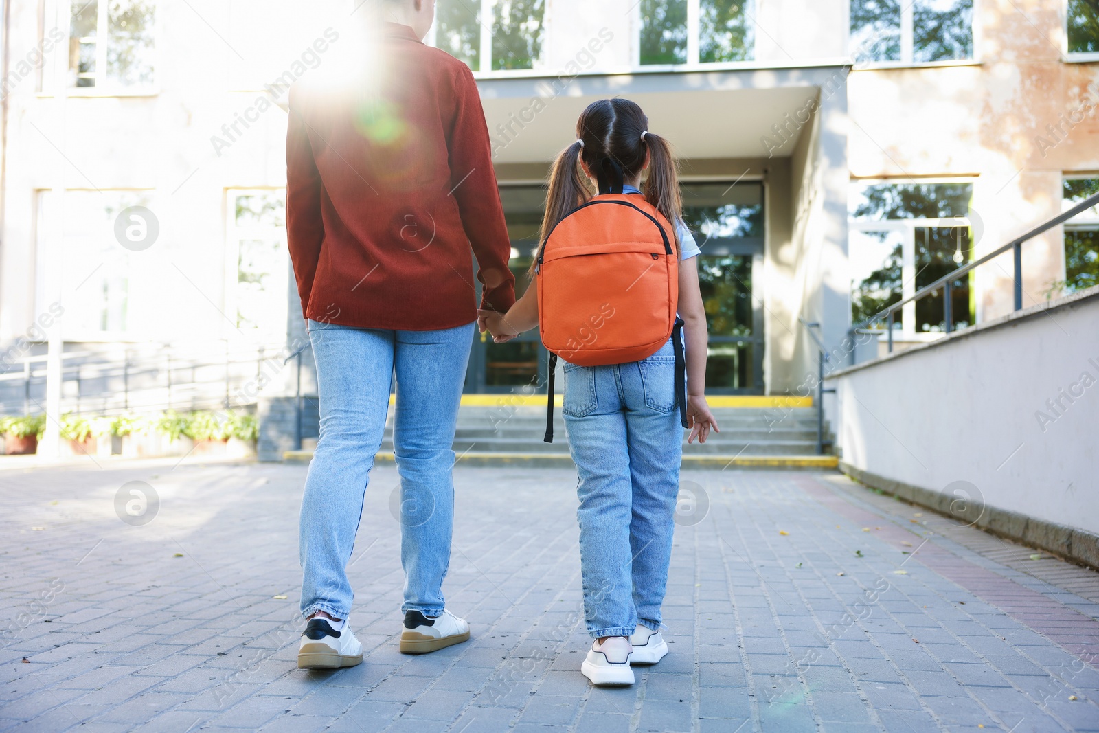 Mother taking her daughter to school outdoors, back view Photo of Mother taking her daughter to school outdoors, back view