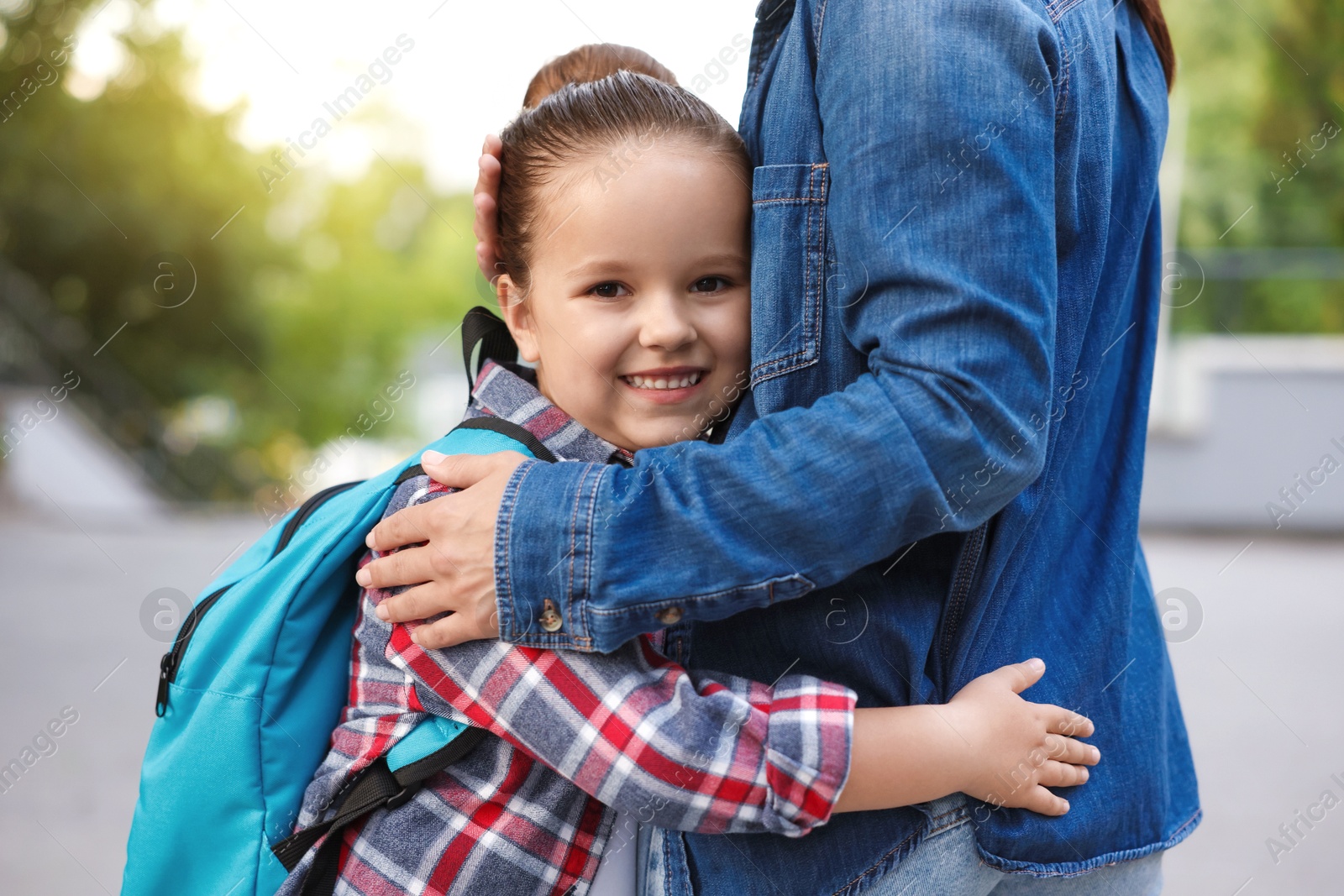 Mother hugging her daughter while taking her to school outdoors, closeup Photo of Mother hugging her daughter while taking her to school outdoors, closeup