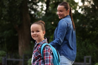 Photo of Mother taking her daughter to school outdoors, selective focus