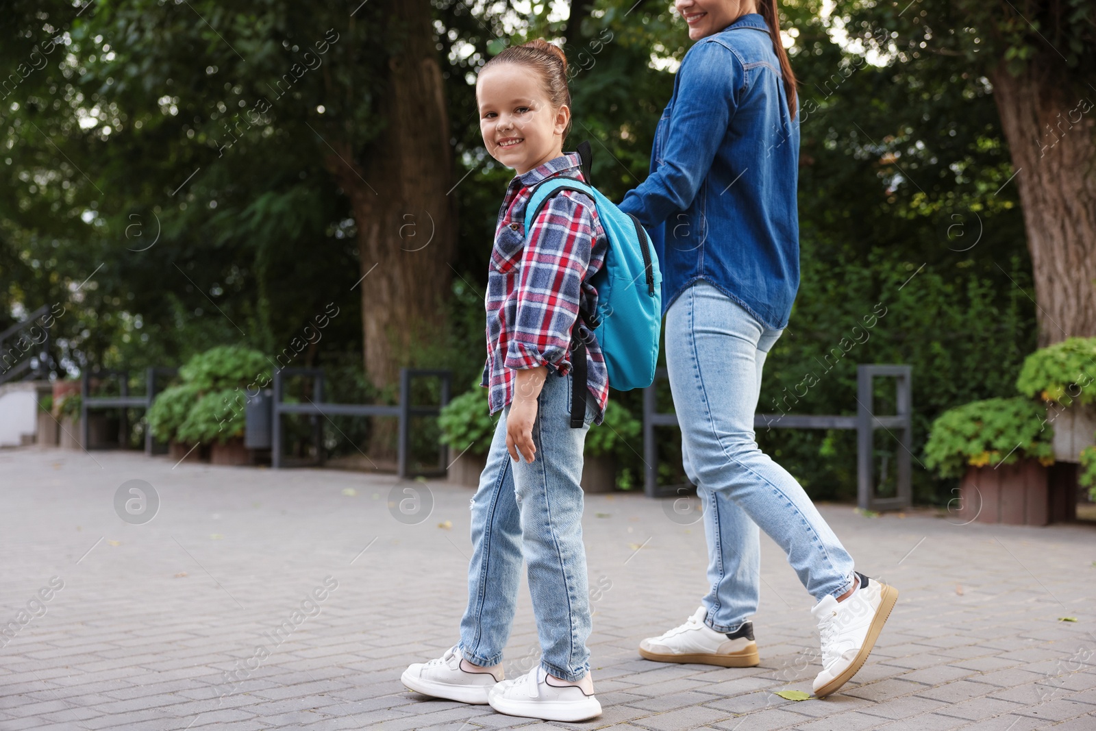 Mother taking her daughter to school outdoors, closeup Photo of Mother taking her daughter to school outdoors, closeup