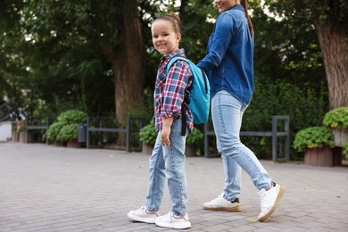 Photo of Mother taking her daughter to school outdoors, closeup