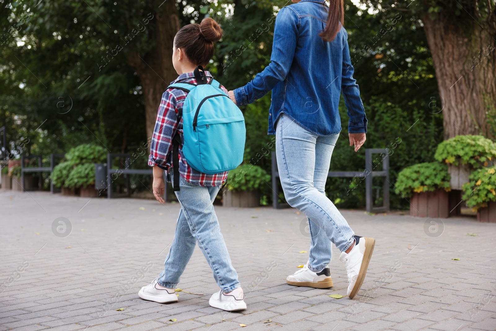 Mother taking her daughter to school outdoors, back view Photo of Mother taking her daughter to school outdoors, back view