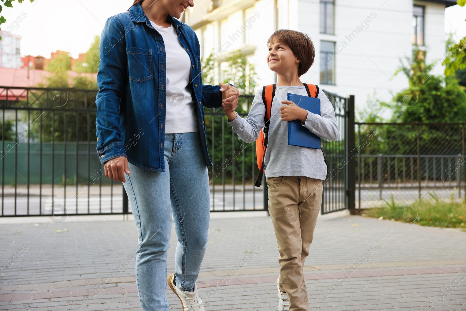 Mother taking her son to school outdoors, closeup Photo of Mother taking her son to school outdoors, closeup