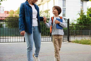 Photo of Mother taking her son to school outdoors, closeup