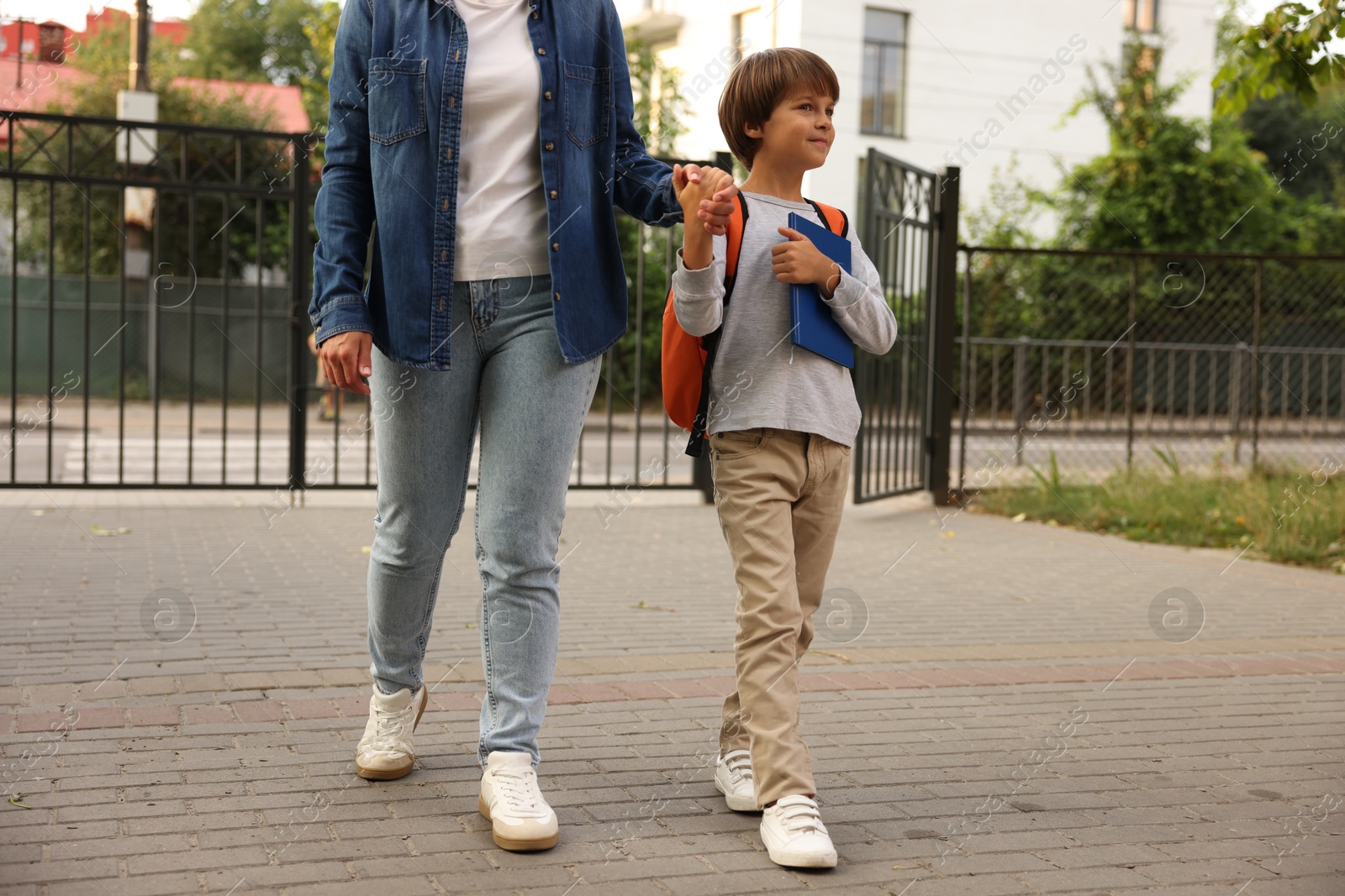 Mother taking her son to school outdoors, closeup Photo of Mother taking her son to school outdoors, closeup