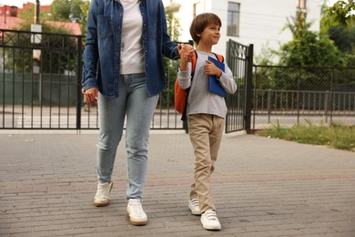 Photo of Mother taking her son to school outdoors, closeup