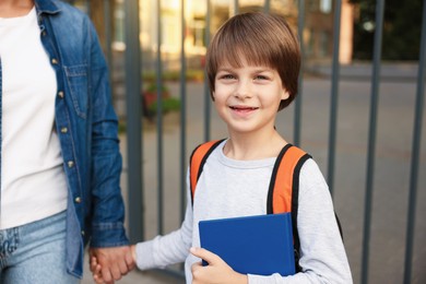 Photo of Mother taking her son to school outdoors, closeup