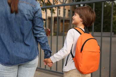 Photo of Mother taking her son to school outdoors, closeup